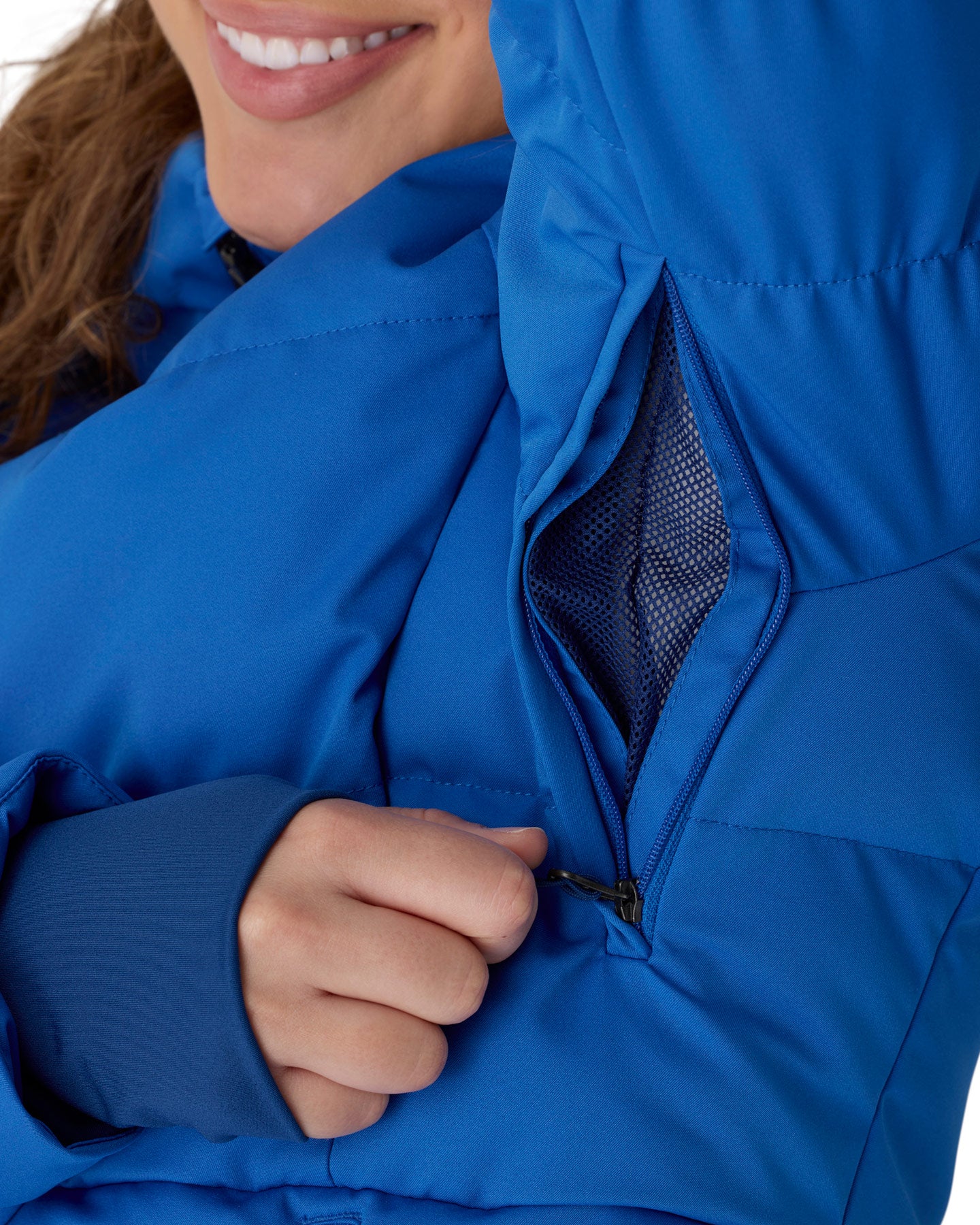 Close-up of a person wearing a bright blue puffer jacket, opening a zippered pocket to show the mesh lining.
